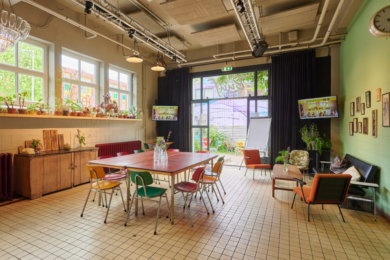 De ruimte van Bie de Buuf met gekleurde stoelen, planten en veel daglicht