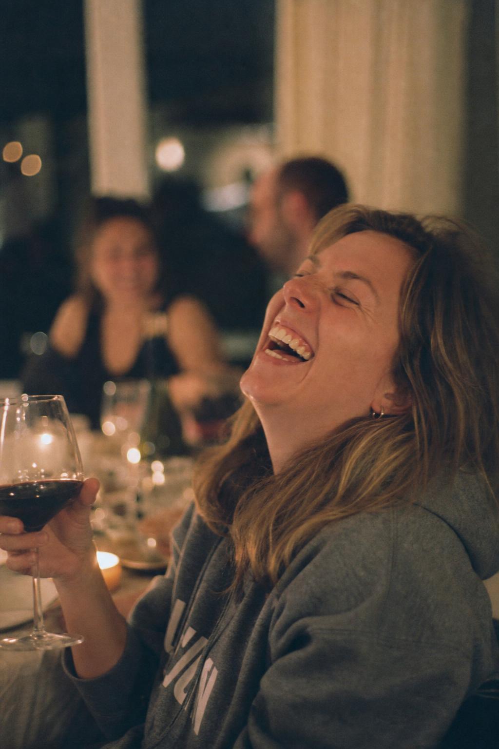Vrouw lacht hard met wijnglas